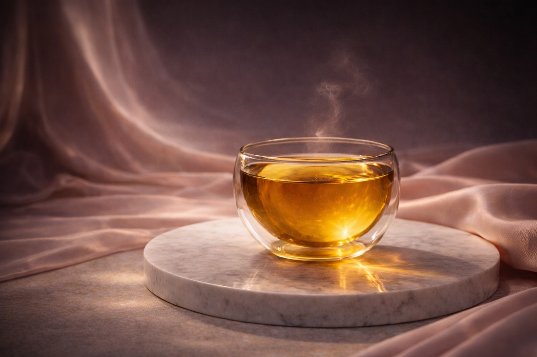 infusion féminine bien-être HazBloom dans tasse en verre, lumière dorée, rituel féminin Hazellia, thé chaud avec vapeur