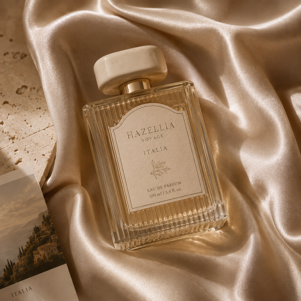 Flacon de parfum Hazellia Voyage Italia posé sur un satin champagne lumineux dans une ambiance luxe inspirée de la Dolce Vita italienne et des maisons de parfum premium.

