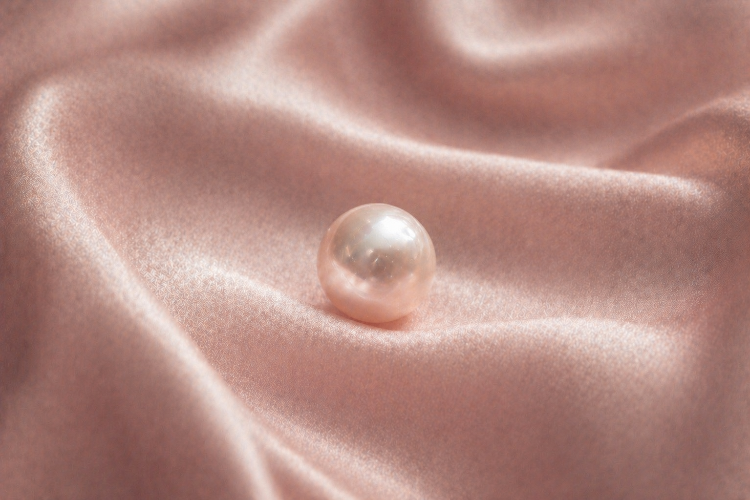 Perle délicate légèrement rosée sur satin rose poudré, lumière douce et ambiance luxe féminin – symbole de féminité et de douceur Hazellia