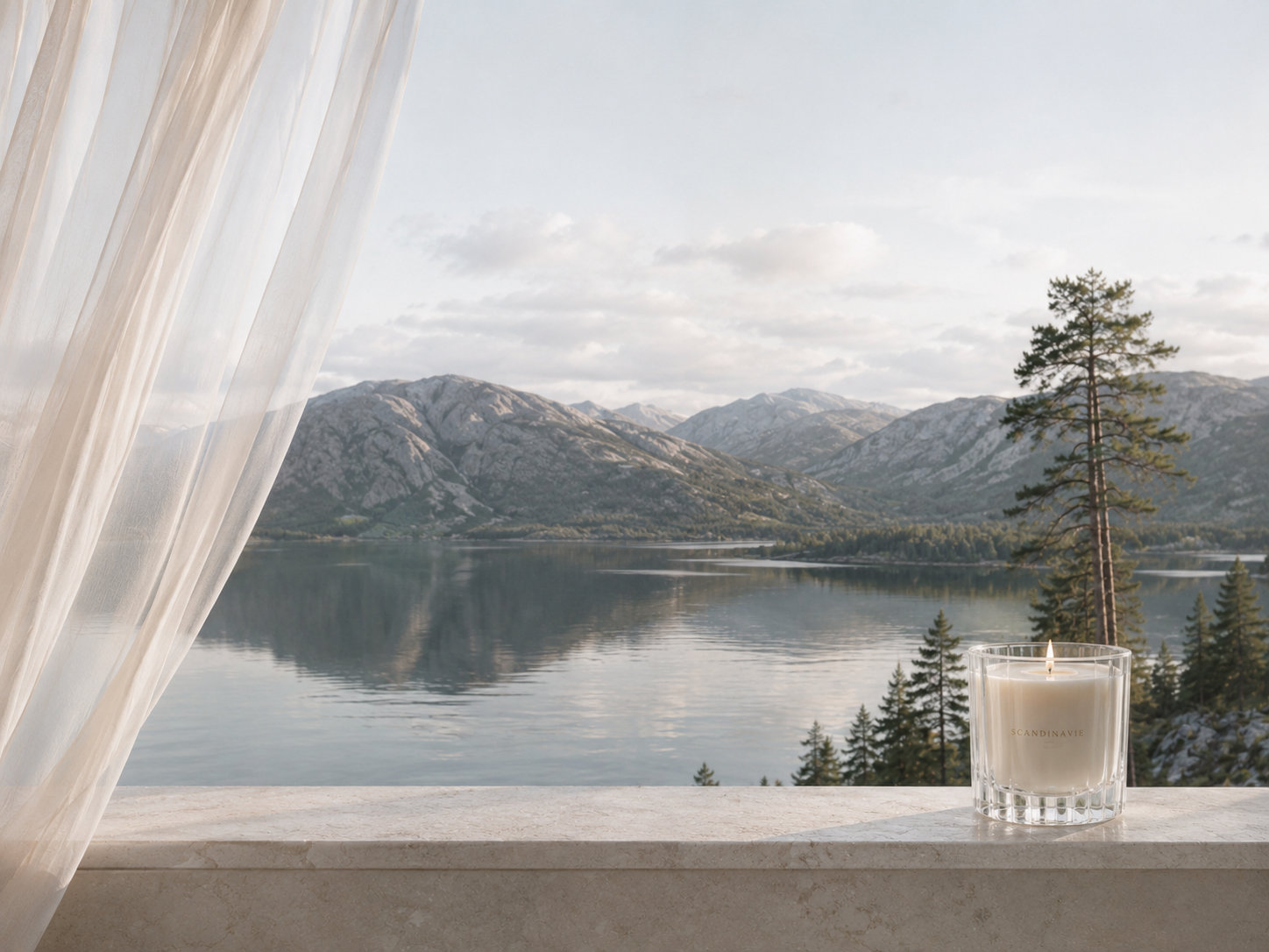 Vue sur un lac scandinave bordé de montagnes, voile aérien ivoire et bougie en verre sur muret en pierre, ambiance Scandinavie Cocooning premium.

