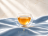 Infusion Zephyr Gleam Hazellia dans un mug en verre sur satin bleu poudré et fond ivoire